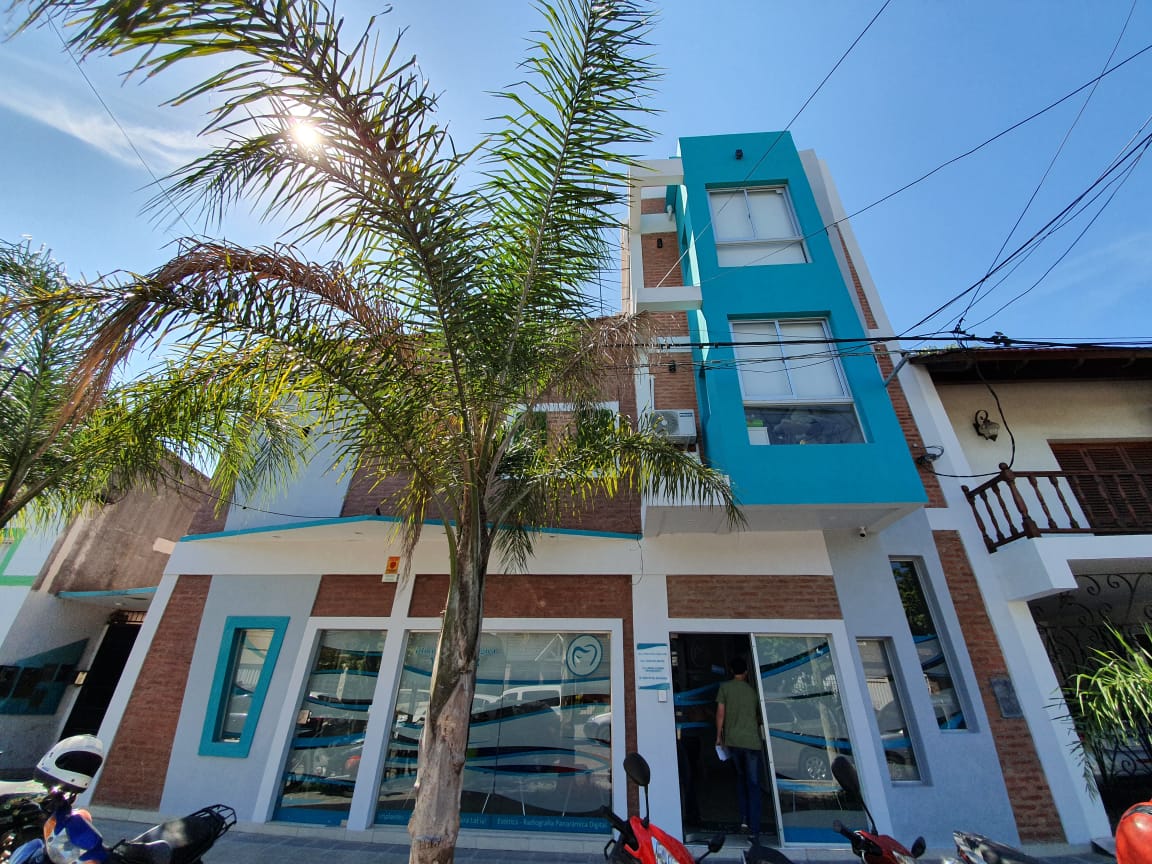 Exterior perspective of Clinica Melgar with clear glass entrance and illuminated street signage